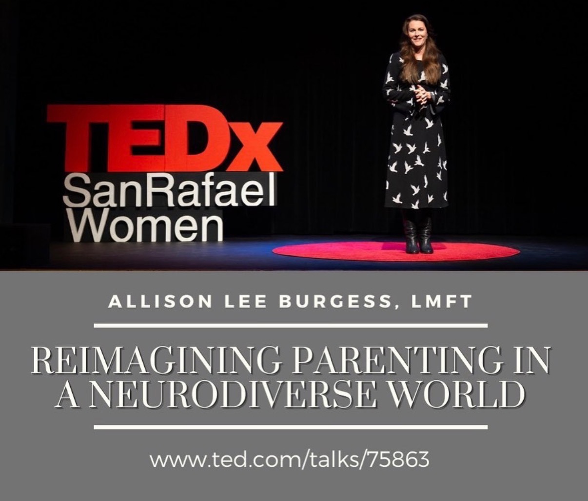 Woman standing on stage with TEDx San Rafael Women sign, wearing a black dress with white patterns, smiling, hands crossed.