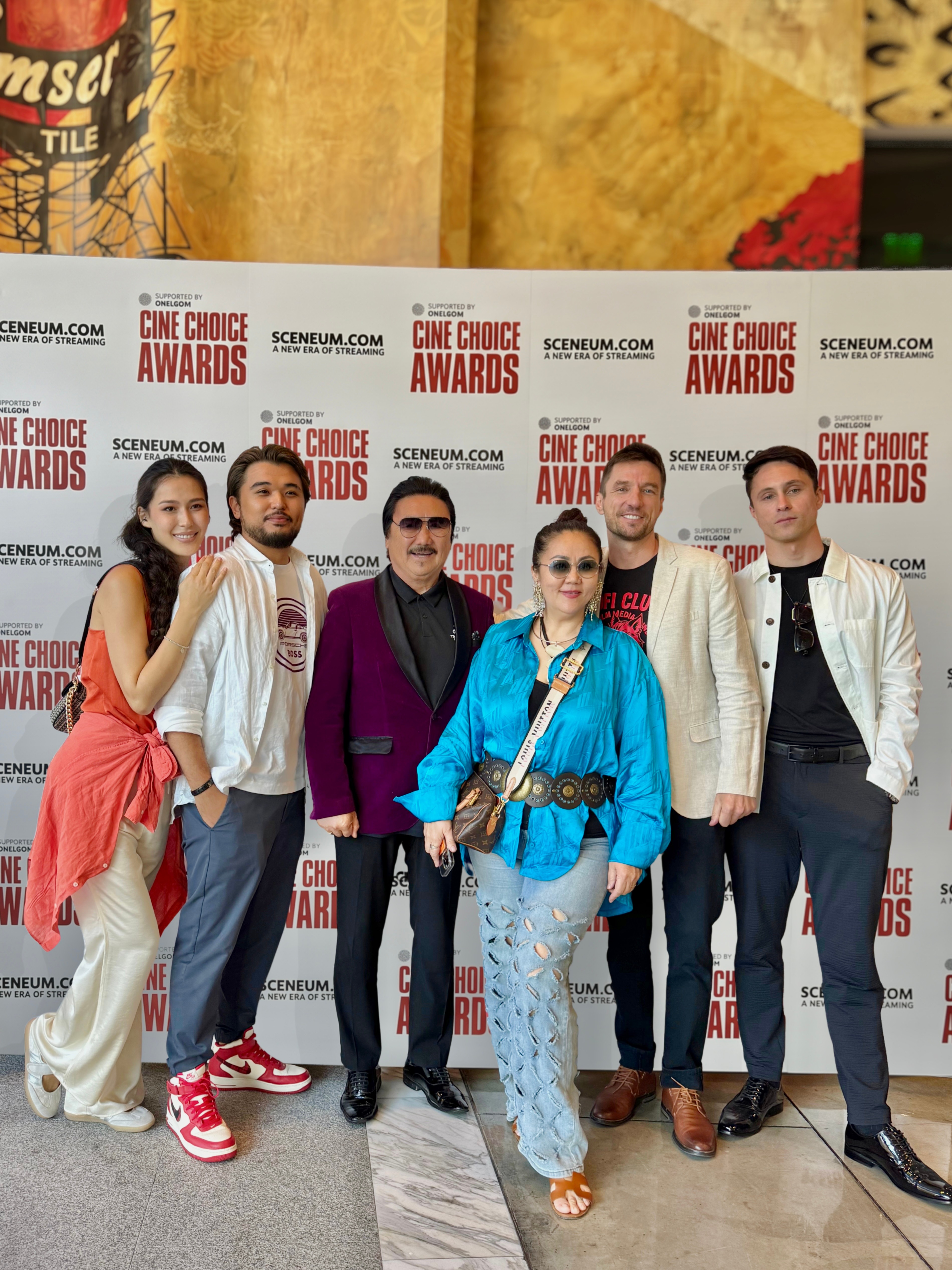 Group of six people standing in front of a backdrop with 'Cine Choice Awards' logo, smiling and posing for the photo.