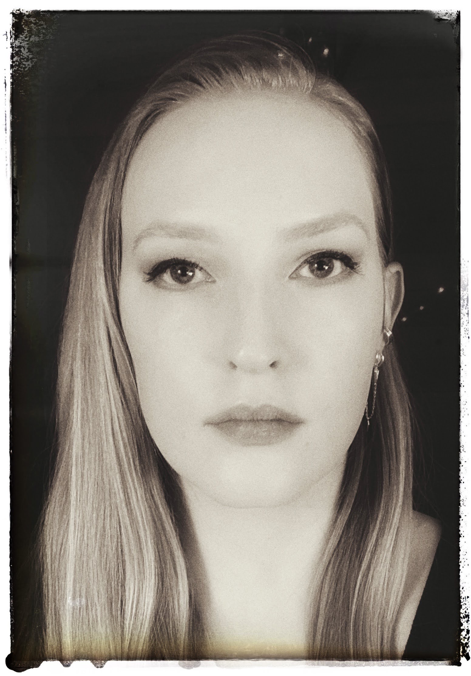 Black and white portrait of a woman with long hair, looking directly at the camera with a neutral expression.